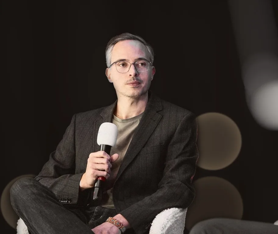 Alessandro Graf sitzt auf der Bühne, mit Mikrofon in der Hand